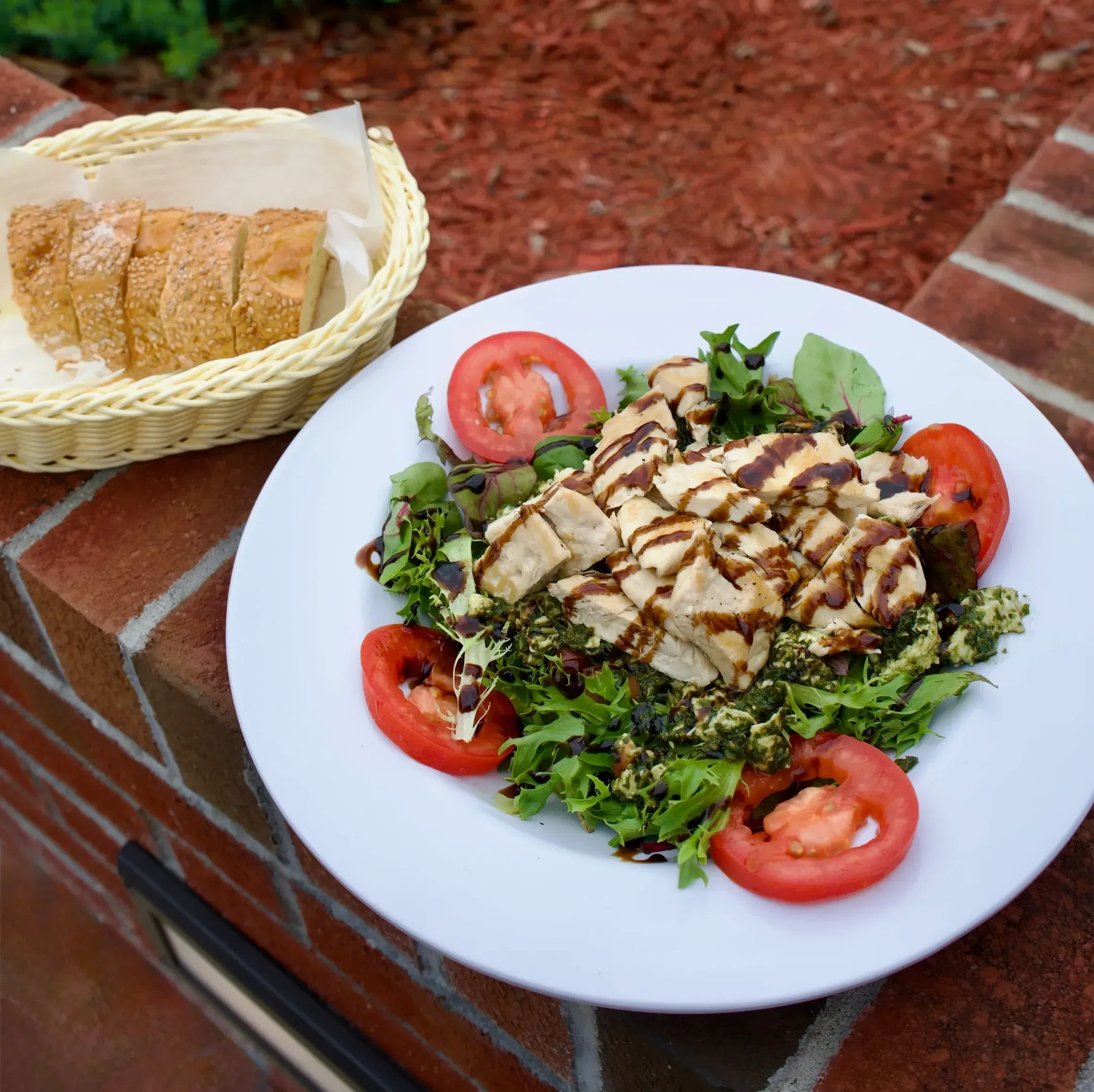 A generous grilled chicken salad with tomato and balsamic