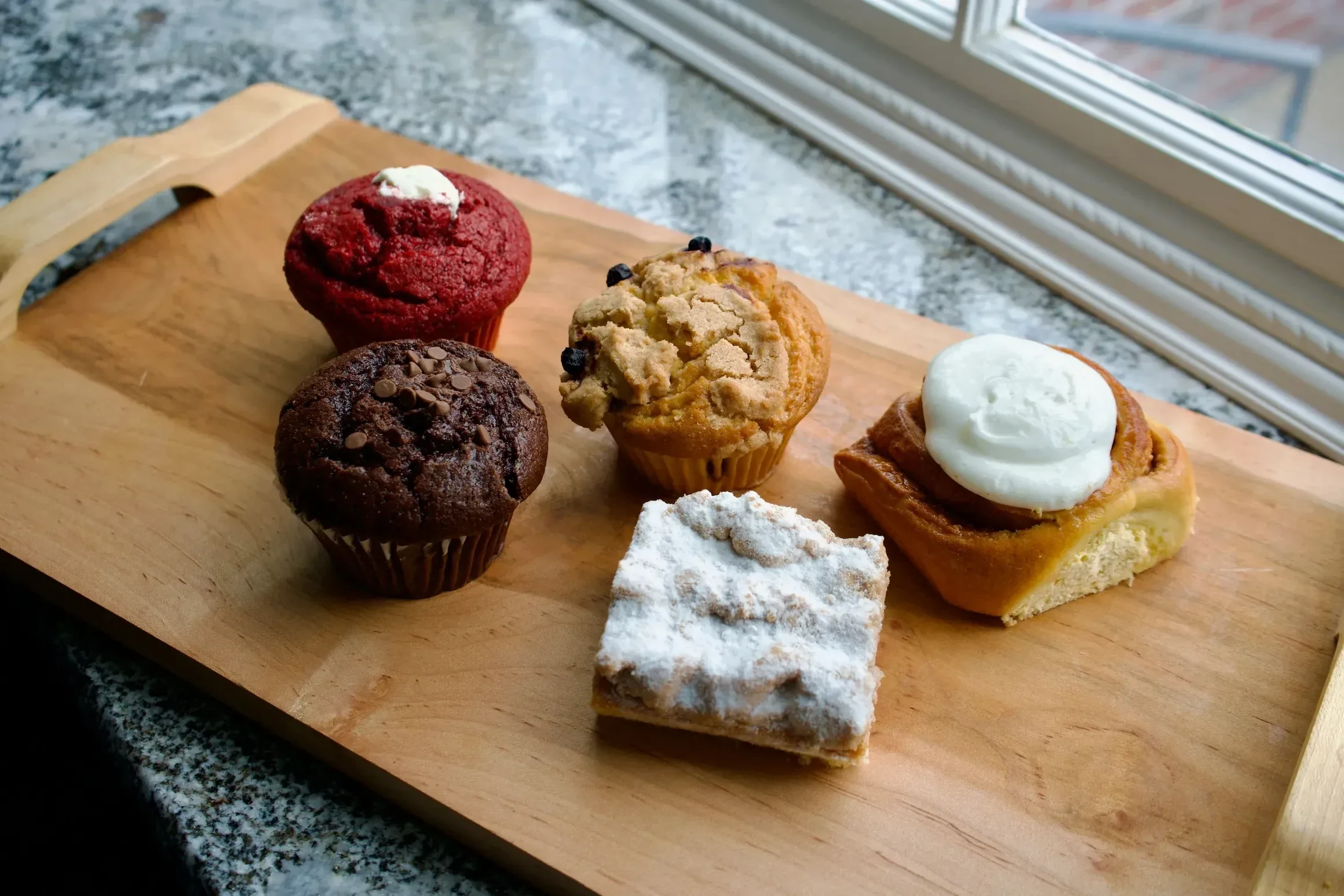A selection of muffins, crumb cake and a frosted cinnamon roll