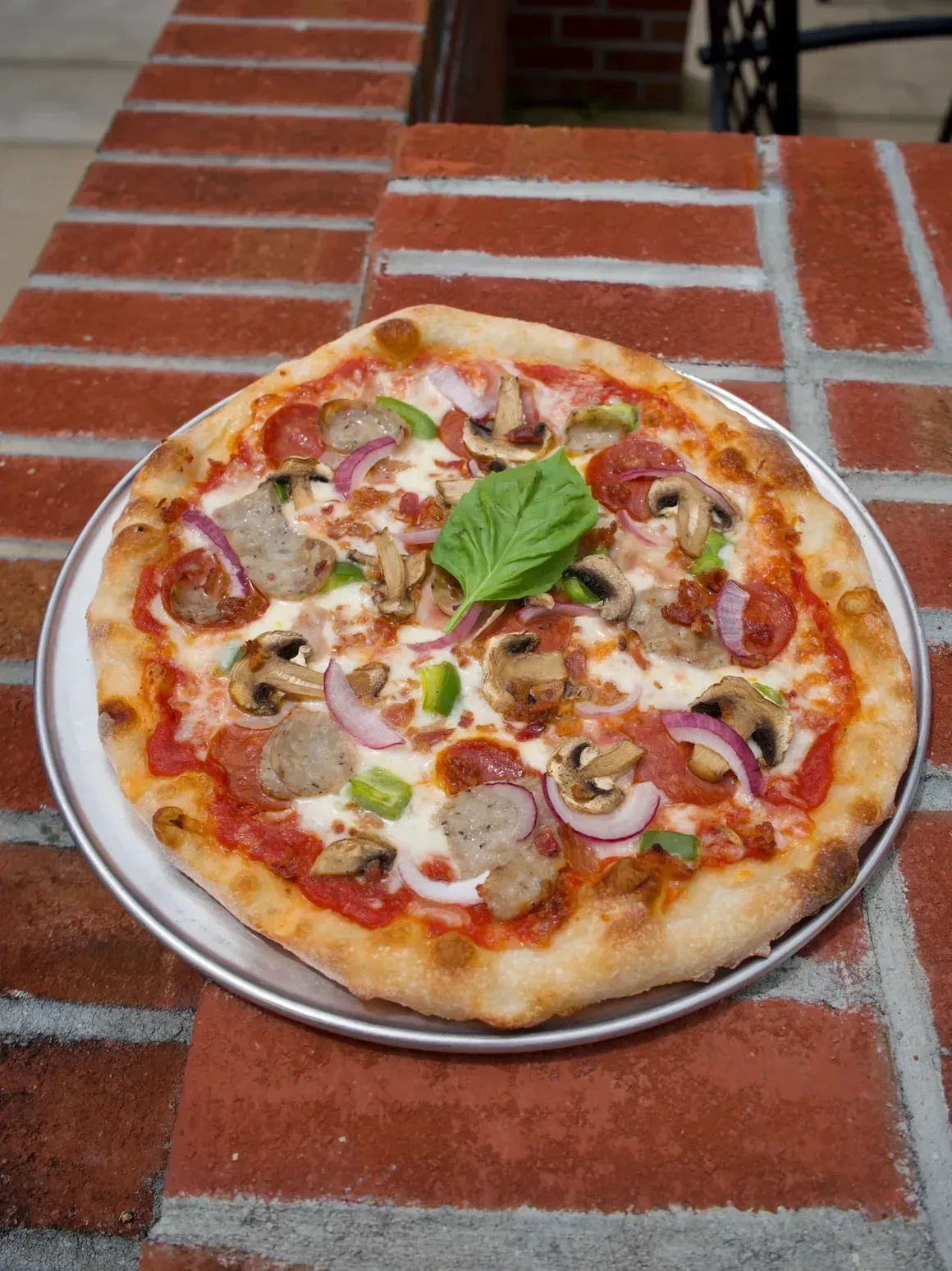A Gemelli pizza with sausage, mushrooms, peppers and basil