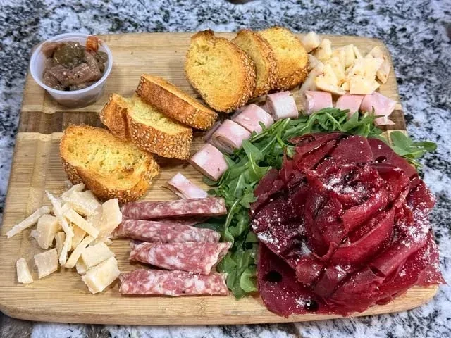 A Gemelli charcuterie board with cured meats, cheeses, arugula and toasted bread